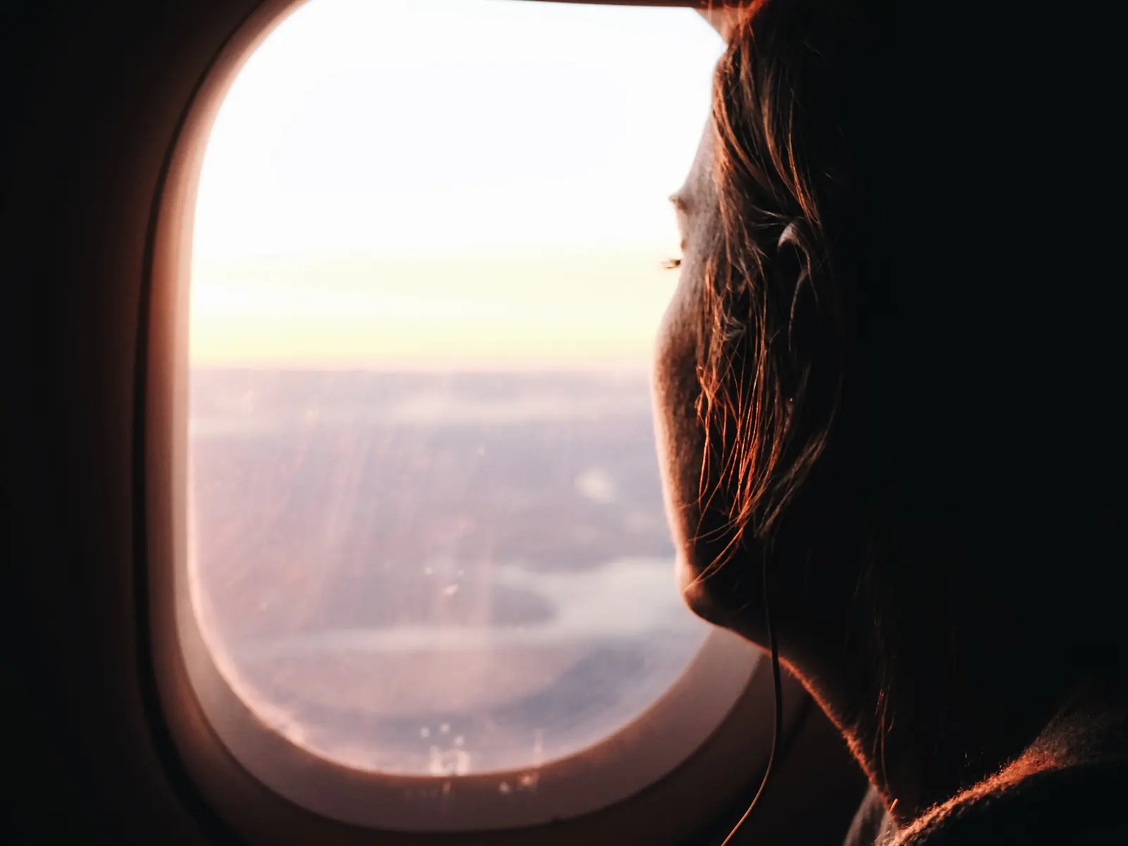 Traveller looking out of an airplane window at sunset