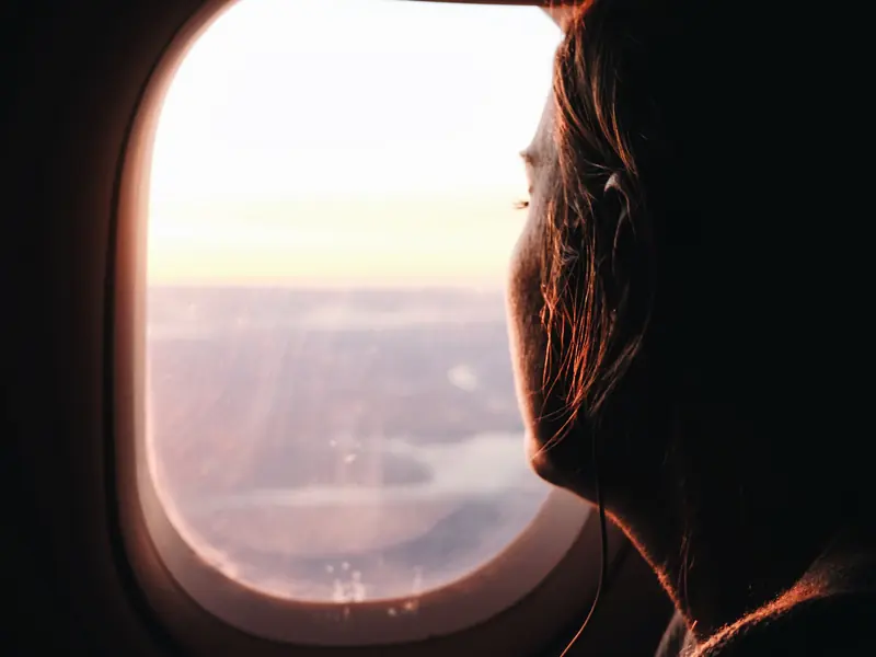 Traveller looking out of an airplane window at sunset